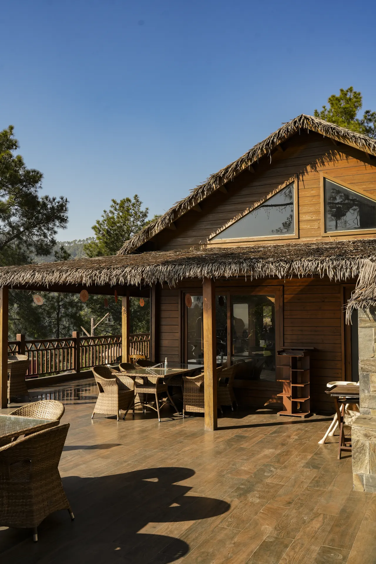 A timber restaurant cabin with a wide deck and chairs under a clear sky