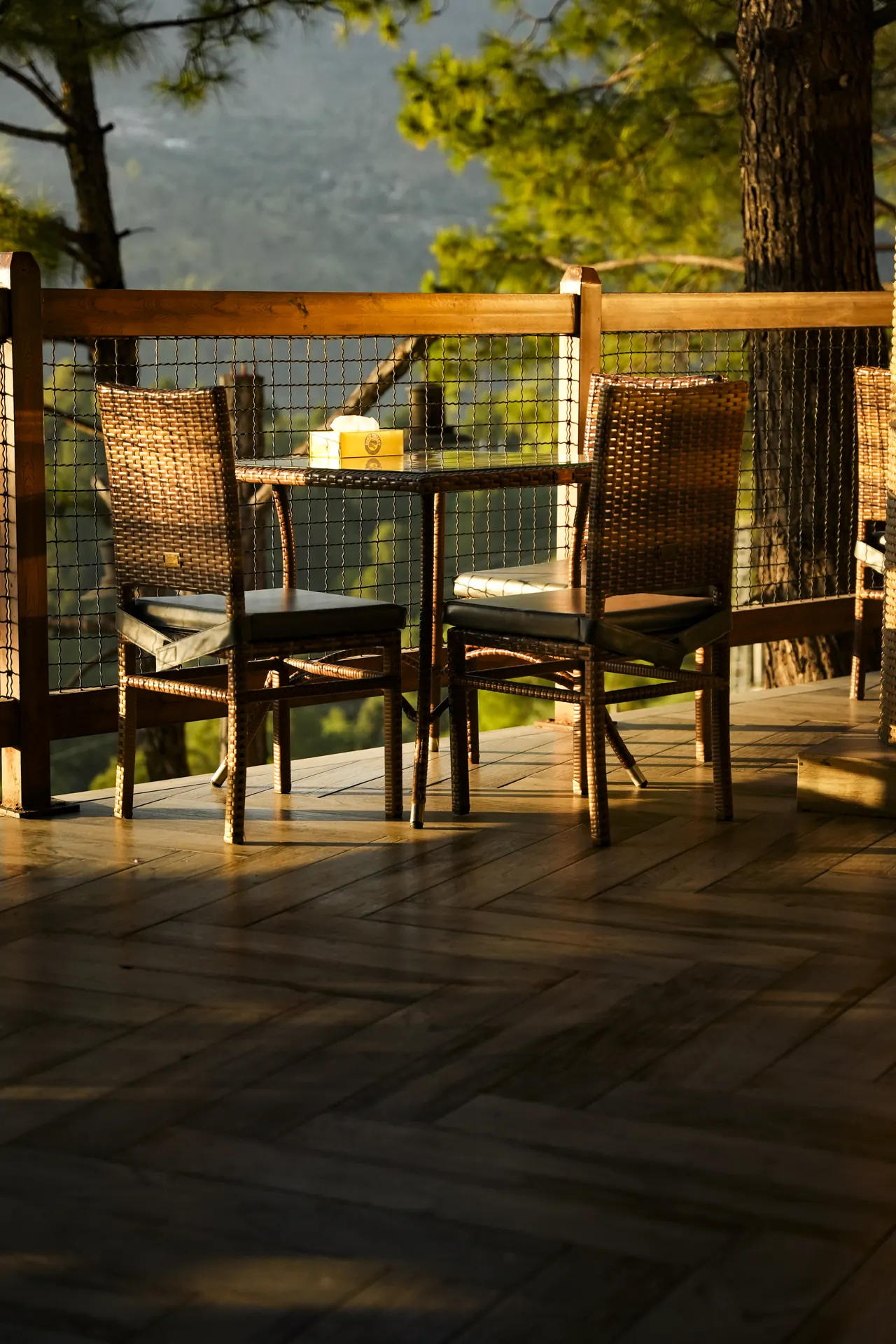 Wicker chairs at a table on a deck in golden light