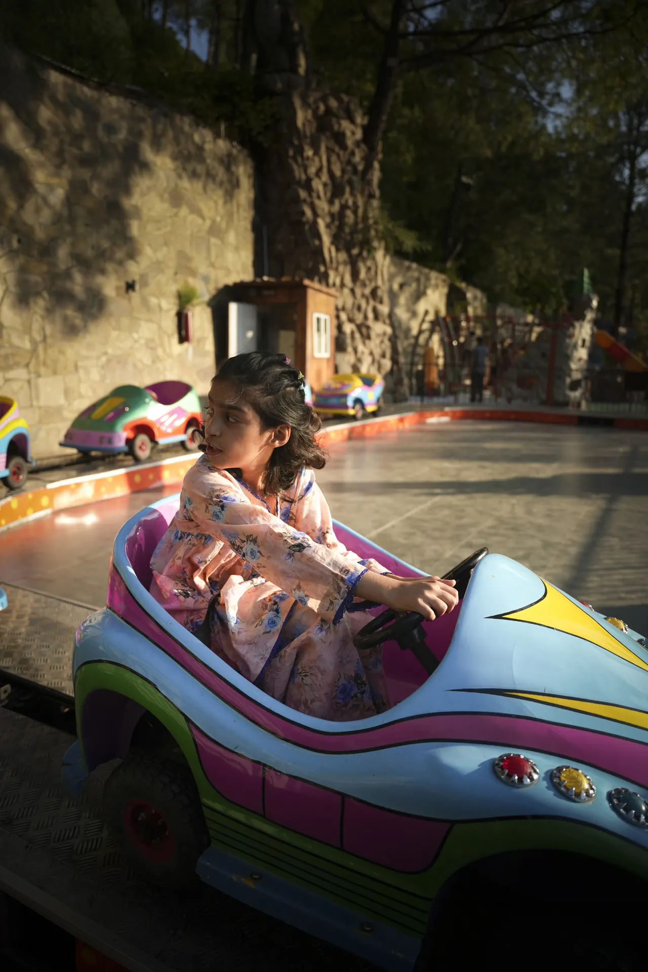 A girl driving a colourful mini car on a small track