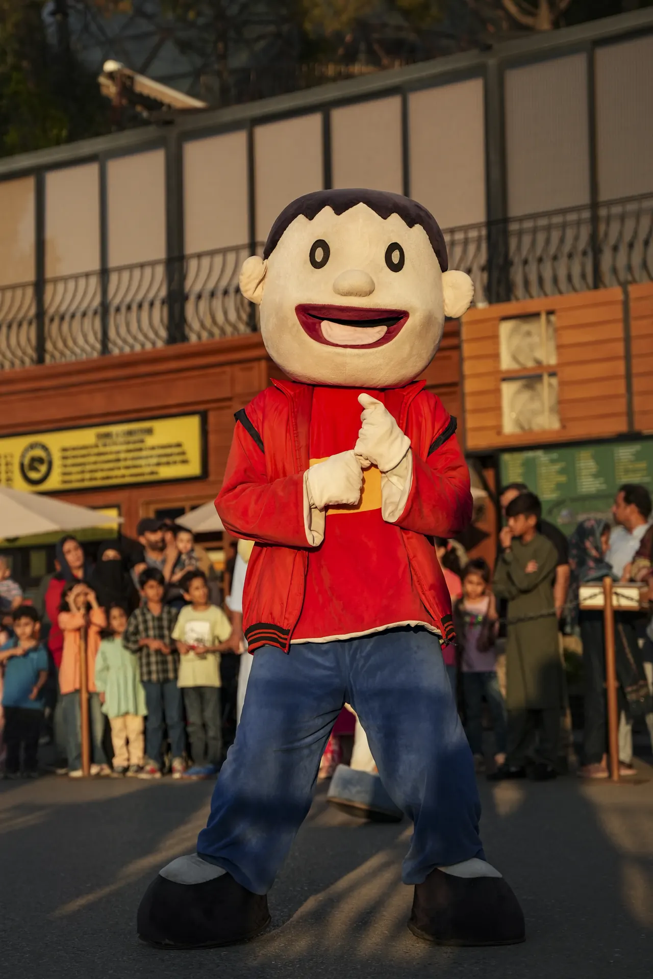 A costume character in a red jacket greeting a crowd of children